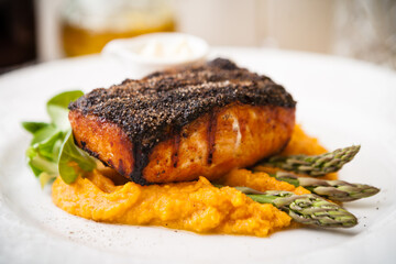 Salmon steak with asparagus and sweet potato mash served on white plate