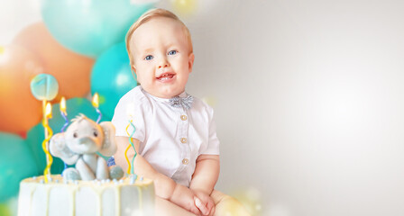 Banner of happy cute little boy (1 year old) with delicious, tasty birthday cake (sweets with candles of number one and decoration).  Celebrating child's first year birthday. Copy space. 