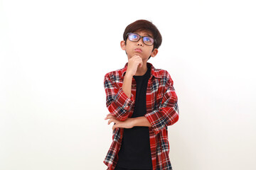 Fototapeta premium Thoughtful asian boy standing while looking above. Isolated on white