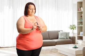 Overweight young woman poking finger with a medical device