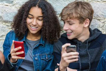 Mixed race African American girl, interracial teenagers boy and girl, male and female, texting and...