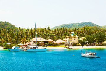 The coast of the island of Martinique in the Caribbean. Yachts, palm trees, beach and turquoise water.