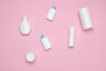 Still life with a set of white small test mockup bottles with cosmetic products for skin and body care, isolated on pink