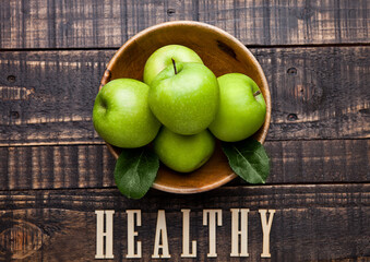 Green organic healthy apples in bowl on wooden board. With sign on the bottom