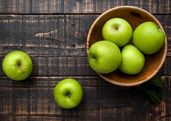 Green organic healthy apples in bowl on wooden board. Healthy food