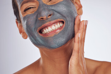 Happy woman, charcoal mask and face for beauty on studio background. Mature female model smile with...