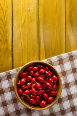 Ripe rosehips in wooden plate on a checkered napkin