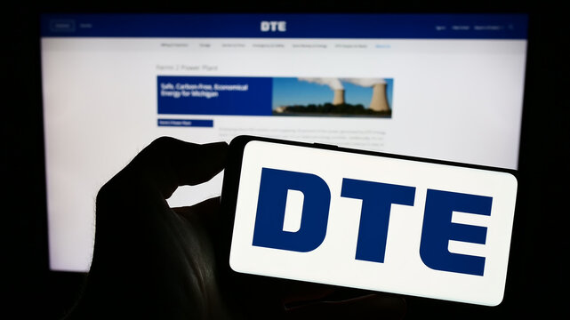 Stuttgart, Germany - 06-30-2023: Person holding cellphone with logo of US utility company DTE Energy Co. on screen in front of business webpage. Focus on phone display.