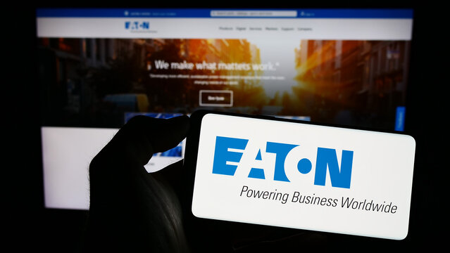 Stuttgart, Germany - 07-01-2023: Person holding smartphone with logo of power management company Eaton Corporation plc on screen in front of website. Focus on phone display.