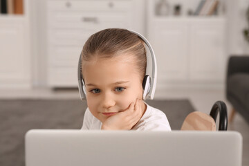 Little girl in headphones using laptop at home. Internet addiction