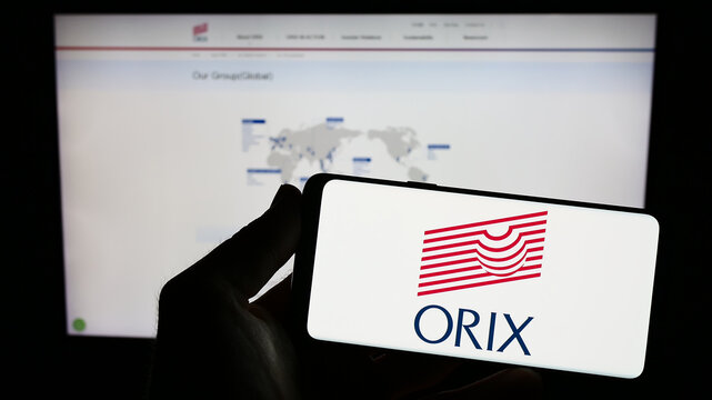 Stuttgart, Germany - 07-01-2023: Person holding smartphone with logo of Japanese financial company ORIX Corporation on screen in front of website. Focus on phone display.