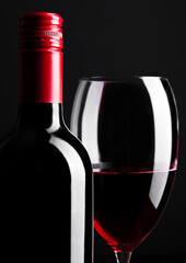 Red wine bottle and glass closeup on black background