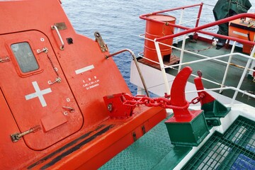 View on release mechanism of orange free fall lifeboat with hook and chain secured on launching...