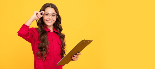 cheerful child girl in glasses making notes, studying. Child builder with protective glasses horizontal poster design. Banner header, copy space.