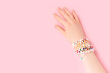 Female hand with a lot of bracelets on it. Trendy handmade jewelry made of pearls and beads on a...