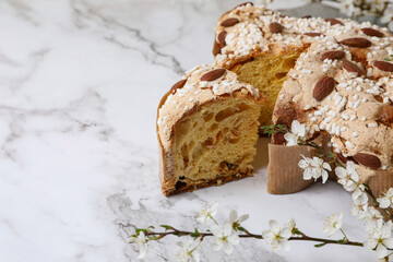 Delicious Italian Easter dove cake (traditional Colomba di Pasqua) and flowers on white marble table, closeup
