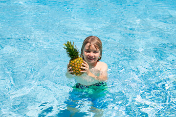 Funny little boy relaxing in a swimming pool, having fun during summer vacation in a tropical resort.