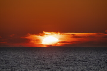 Photo of a seascape, sunset, the sun goes beyond the horizon, close-up photo.