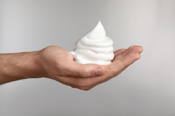 Man holding shaving foam on light grey background, closeup