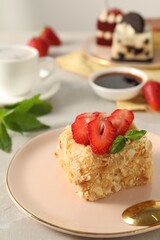 Piece of delicious Napoleon cake with fresh strawberries on light table, closeup. Space for text
