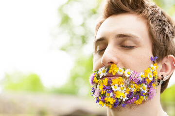 portrait of a guy with flowers instead of his beard relaxed in the nature