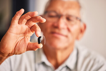 Hand holding hearing aid, senior man and tech for ears, health and wellness for retirement in nursing home. Elderly person with disability, audio or sound technology to listen in closeup at house - obrazy, fototapety, plakaty