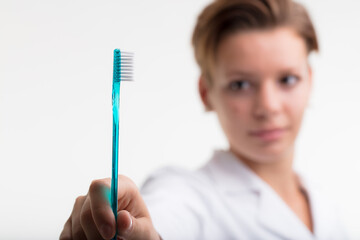 concept of toothbrush in focus held by a dentist suggesting to brush your teeth on a daily basis