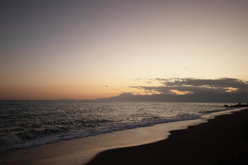 Obraz premium Beautiful view of the sea, waves and mountains at sunset. The horizon above the water.