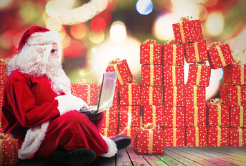 Santa Claus with a laptop and gift packs on background