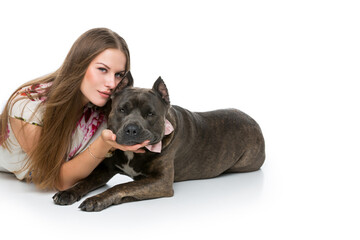 Obraz premium Beautiful elegant happy young woman in white dress hugging adult grey amstafford terrier dog with bow on neck. Isolated on white background. Copy space.