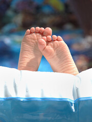 The Feet of a Young Child Proped Up on the Top of His Inflatable Swimming Pool - 622355465