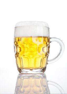 Vintage glass of beer with foam with reflection on white background