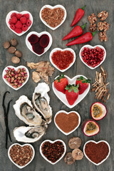 Aphrodisiac food selection with foods in porcelain heart shaped bowls and loose on marble background.