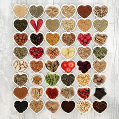 Aphrodisiac food for sexual health in heart shaped bowls over distressed white wood background.