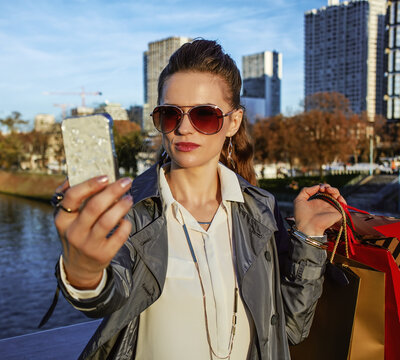 Get your bags ready for the Paris autumn sales. Portrait of young trendy woman with shopping bags taking selfie with mobile phone in Paris, France