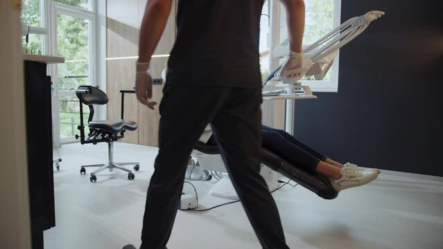 Woman patient sits in the dental chair. Assistants and man dentist start the procedure. Hydience and healthy.