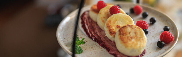 Cheesecakes served on plate with berries, cream and sugar powder ready for eating in restaurant