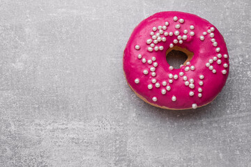 Tasty glazed donut decorated with sprinkles on light grey table, top view. Space for text