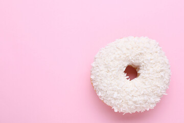 Tasty glazed donut with coconut shavings on pink background, top view. Space for text