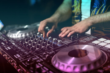 DJ Hands creating and regulating music on dj console mixer in concert party night club