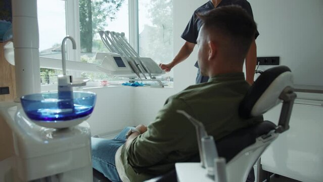Man sits in a dental chair. Dentist hold a dental instrument starting treats teeth. Hydience and health. Modern clinic