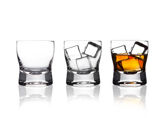 Glasss of whiskey with ice cubes with reflection on white background