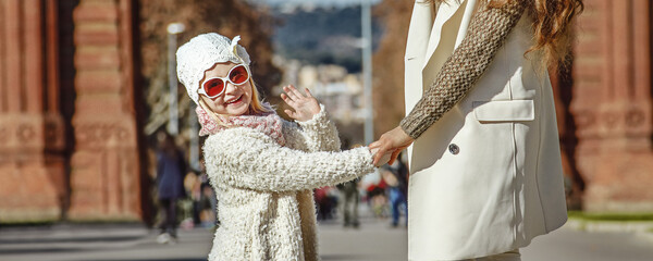 in Barcelona for a perfect winter. Full length portrait of happy young mother and child near Arc de...