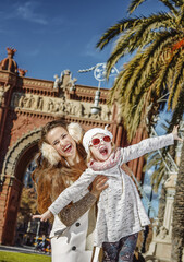 Obraz premium in Barcelona for a perfect winter. Portrait of smiling trendy mother and daughter near Arc de Triomf in Barcelona, Spain having fun time