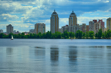 Fototapeta premium Picturesque panoramic landscape view of Obolon embankment with skyscrapers in the background. Popular place for recreation among locals and tourists.