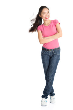 Portrait of happy young Asian woman in pink shirt and jeans with ponytail hair, full length standing isolated on white background.