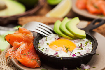 Fried egg, avocado and smoked salmon in frying pan served for breakfast