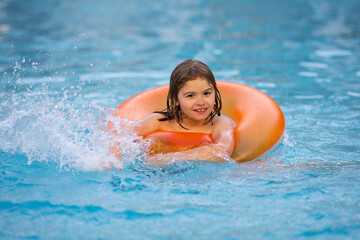 Child play in pool on inflatable ring. Kid with inflatable ring in swimming pool. Child water toys. Children play in tropical resort. Child in swiming pool. Kid floating in sea.