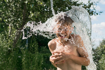 A little boy is doused with water