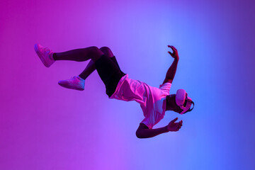 african american male gamer in virtual reality glasses flies in the air and falls in neon lighting,...